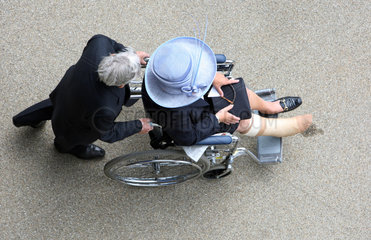 Ascot  Grossbritannien  Mann schiebt eine elegant gekleidete Frau im Rollstuhl