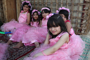 Dubai  Vereinigte Arabische Emirate  Maedchen in rosa Kleidern sitzen auf dem Boden