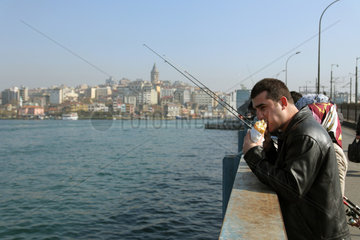 Istanbul  Tuerkei  Angler mit einem Snack auf der Galatabruecke