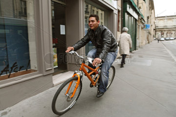 Nancy  Frankreich  ein junger  laechelnder Mann faehrt mit dem Fahrrad