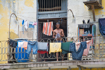 Havanna  Kuba  ein Mann haengt Waesche auf dem Balkon auf