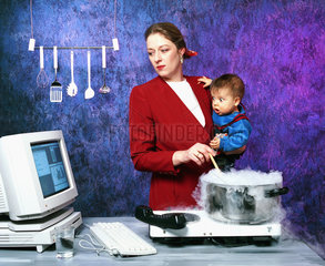 Hamburg  Deutschland  kochende Mutter mit Kind auf dem Arm schaut auf Computermonitor