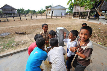 Sre Ambel  Kambodscha  Jungen trinken Wasser aus einem Brunnen