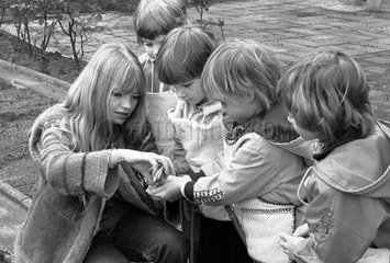 Berlin  DDR  Lehrerin gibt einem Kind bei der Gartenarbeit im Schulgarten Pflanzensamen in die Hand