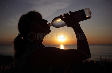 Kaegsdorf  Deutschland  Silhouette  eine Frau trinkt Wasser aus einer Flasche