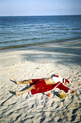 Weihnachtsmann liegt am Strand