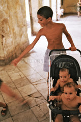 Havanna  Kuba  Junge schiebt seine Geschwister im Kinderwagen