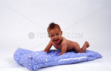 Baby mit Iro auf Decke