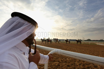 Dubai  Vereinigte Arabische Emirate  Araber beobachtet Pferde und Reiter beim Training auf der Galopprennbahn