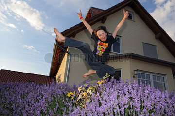 Werl  Deutschland  Junge macht einen Luftsprung vor einem Einfamilienhaus