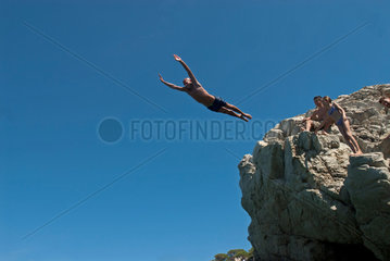Portoferraio Italien  ein Mann springt von einem Felsen in der Bucht Sansone
