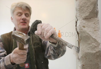 Berlin  Deutschland  Handwerker bearbeitet eine Wand mit Hammer und Meissel