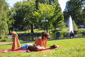 Essen  Deutschland  Ruhrgebiet  Stadtgarten  junge Frau liegt auf der Wiese und liest in einem Buch