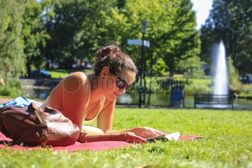 Essen  Deutschland  Ruhrgebiet  Stadtgarten  junge Frau liegt auf der Wiese und liest in einem Buch