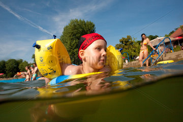 Berlin  Deutschland  Junge mit Schwimmfluegeln und Deutschlandbadekappe
