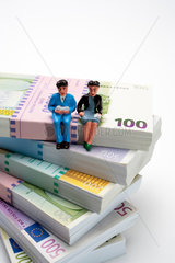 Freiburg  Deutschland  Renterfiguren sitzen auf einem Stapel mit Euroscheinen