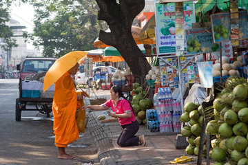 Phnom Penh  Kambodscha  eine Frau gibt einem buddhistischen Moench Opfergaben