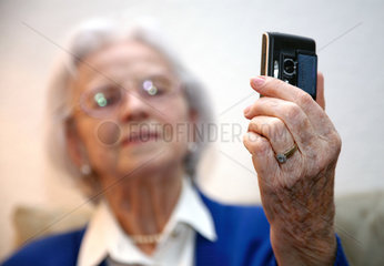 Berlin  Deutschland  eine aeltere Frau macht mit ihrem Handy ein Foto