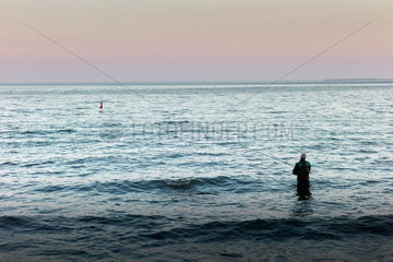 Ostseeinsel Ruegen  Mecklenburg-Vorpommern  Deutschland - Angler fischt im Wasser stehend