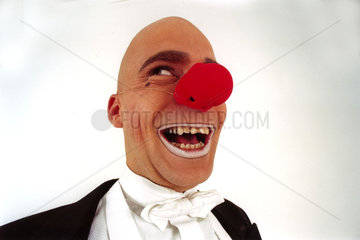 Clown in Anzug und mit roter Nase