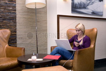 Berlin  Deutschland  eine blonde Frau mit Laptop und Mobiltelefon in einem Cafe