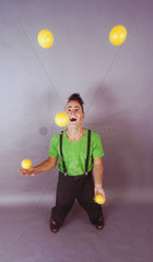 Clown jongliert mit fuenf Baellen