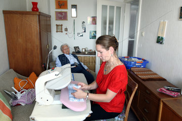 Berlin  Deutschland  eine junge Frau hilft einer Seniorin beim Buegeln