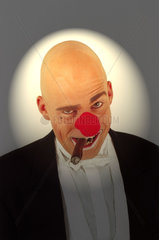 Clown in Anzug und mit roter Nase und Zigarre