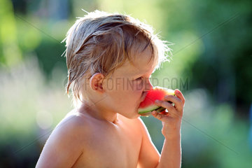 Berlin  Deutschland  Junge isst ein Stueck Wassermelone