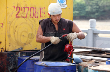 Hong Kong  China  Mann pumpt Diesel aus einer Blechtonne ab