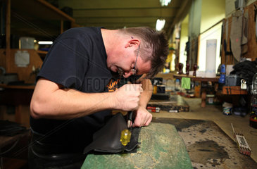 Haage  Deutschland  Handwerk  Mann bearbeitet Leder in einer Sattlerei