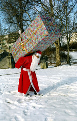 Weihnachtsmann traegt Riesenpaket