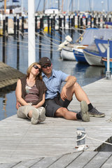 Kiel  Paar sitzt auf einem Bootssteg im Hafen