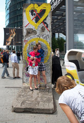 Berlin  Deutschland  Touristen posieren vor einem Teilstueck der Berliner Mauer
