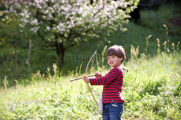 Carabietta  Schweiz  Junge spielt mit Pfeil und Bogen auf einer Wiese