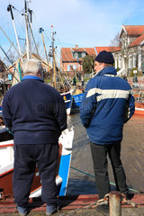 Neuharlingersiel  Deutschland  zwei Fischer stehen am Fischereihafen