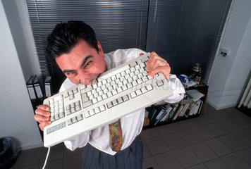 Mann beisst in Tastatur