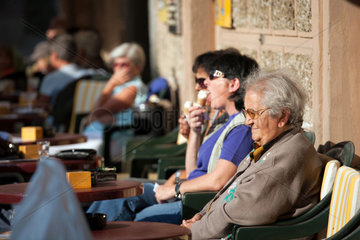 Puschlav  Schweiz  aeltere Frau geniesst die Sonne im Caffe Semadeni Garni am Marktplatz