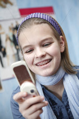 Hamburg  Deutschland  ein elfjaehriges Maedchen mit Zahnspange spielt mit dem Handy