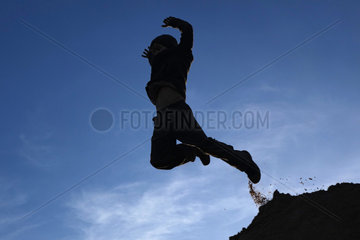 Schependorf  Deutschland  Silhouette  ein Junge macht einen Luftsprung
