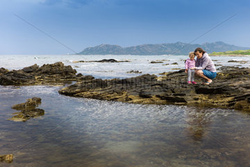 Eine Mutter mit Kind an der Steinkueste auf Sardinien