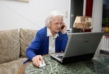 Berlin  Deutschland  eine alte Frau sitzt am Laptop und telefoniert