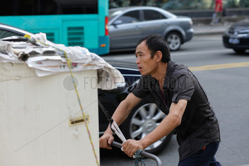 Shenzhen  China  ein Mann schiebt einen schwer beladenen Karren