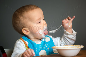 Berlin  Deutschland  ein Kleinkind mit Schnute isst Joghurt mit einem Loeffel