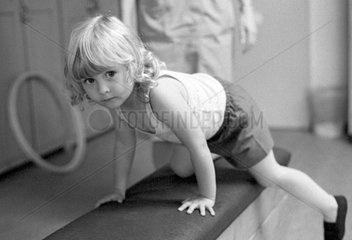 Berlin  DDR  kleines Maedchen turnt in einer Kindertagesstaette auf einem Kasten