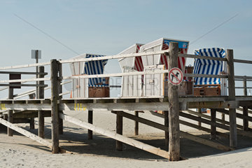 Strandkoerbe auf einem Holzsteg am Strand von Boehl