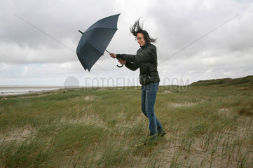 Sankt Peter-Ording  Deutschland  eine Frau geht bei Sturm und Regen am Strand spazieren