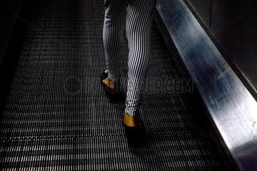 London  Grossbritannien  Maedchen mit gestreifter Hose auf einer Rolltreppe