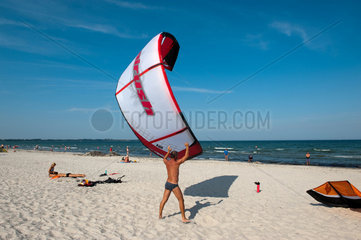 Glowe  Ruegen  Deutschland  ein Mann hilft einem Kite-Surfer am Strand