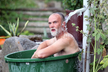 Neu Kaetwin  Deutschland  Mann badet in einer Regenwassertonne